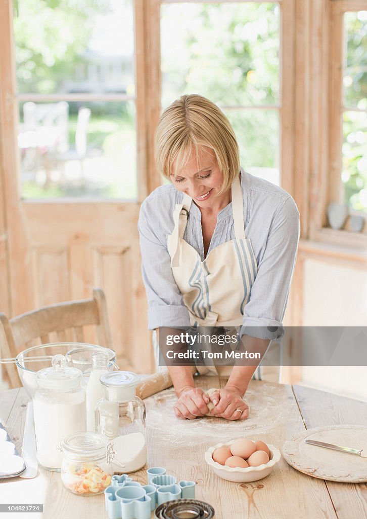 Donna sorridente Impastare pasta sul tavolo della cucina
