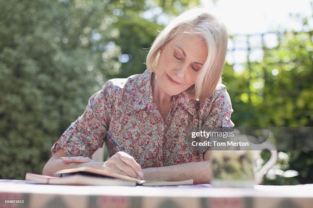 Woman writing in journal at patio table