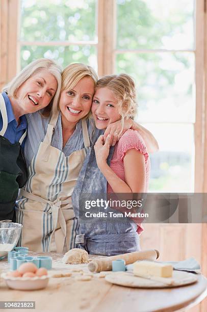 smiling multi-generation females hugging and baking in kitchen - pastry cutter stockfoto's en -beelden