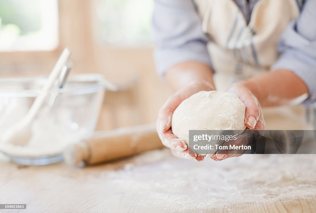 Woman holding ball of dough in kitchen