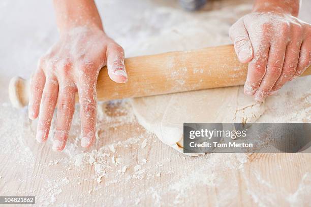 close up of woman rolling dough with rolling pin - deegrol stockfoto's en -beelden