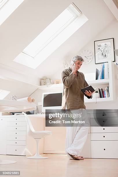 man talking on phone and looking at schedule in office - skylight stock pictures, royalty-free photos & images