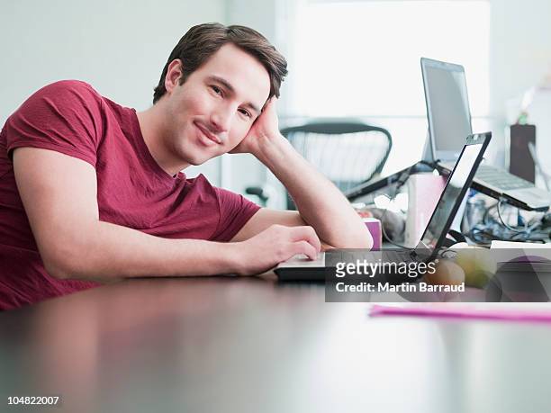 empresário sorridente usando laptop e inclinado em mesa de escritório - couch potato expressão em inglês - fotografias e filmes do acervo
