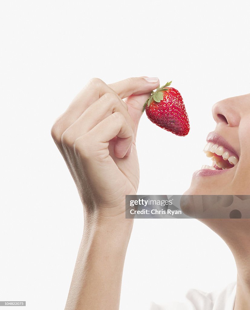 Smiling woman eating strawberry