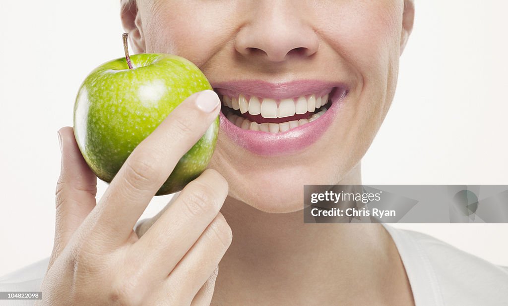 Primo piano di donna sorridente con mela verde