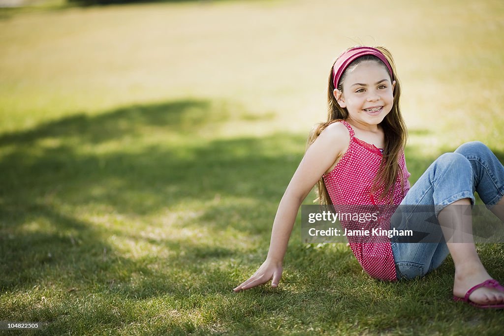 Young girl sitting on grass laughing