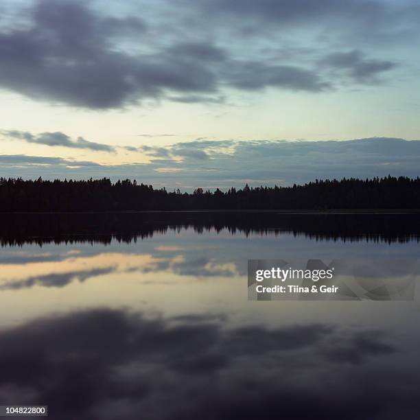 sky and trees reflected in lake at night - somero photos et images de collection