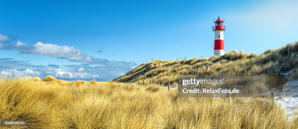 Red and white striped lighthouse on sand dunes of island Sylt in winter