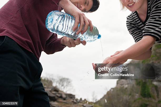 man pouring water onto womans hands - water bottle splash stock pictures, royalty-free photos & images