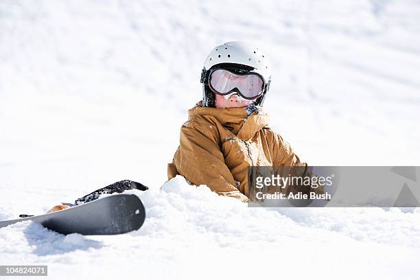 young boy covered in snow with skis - skipiste stockfoto's en -beelden