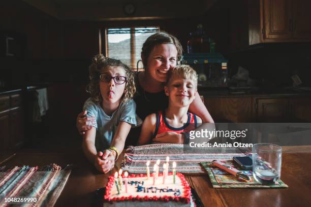 Mother and children sitting by a birthday cake