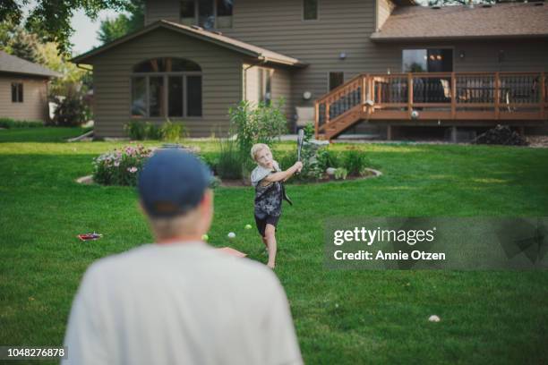 boy playing backyard baseball with his dad - backyard baseball stock pictures, royalty-free photos & images