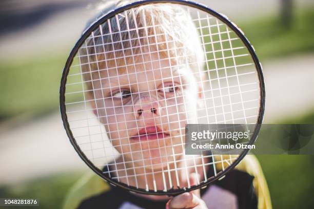 boy pressing his face against a badminton racket - playing badminton stock-fotos und bilder