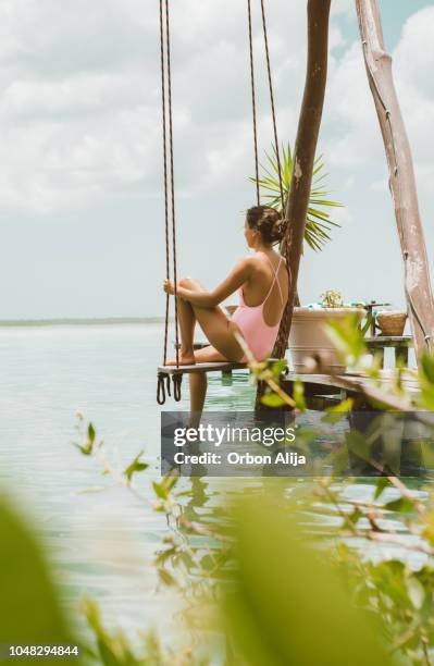 vrouw zitten op een schommel op een lagune - yucatán schiereiland stockfoto's en -beelden