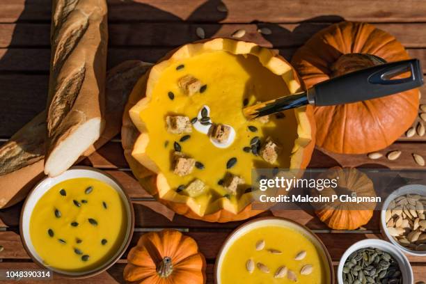 pumpkin soup in shell with soup in bowls with bread and seeds. - pumpkin soup stock pictures, royalty-free photos & images