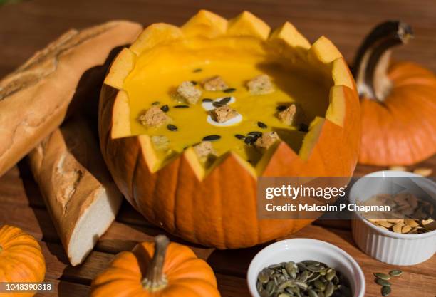 pumpkin soup in shell with soup in bowls with bread and seeds. - pumpkin soup stock-fotos und bilder
