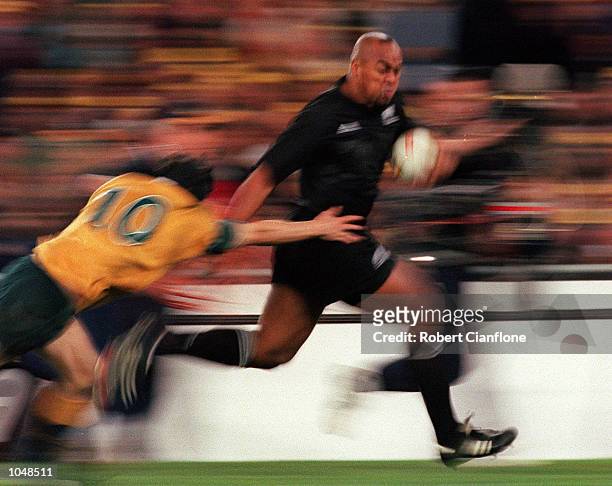 Jonah Lomu of New Zealand evades the tackle of Stephen Larkham of Australia during the match between Australia v New Zealand for the Bledisloe Cup at...
