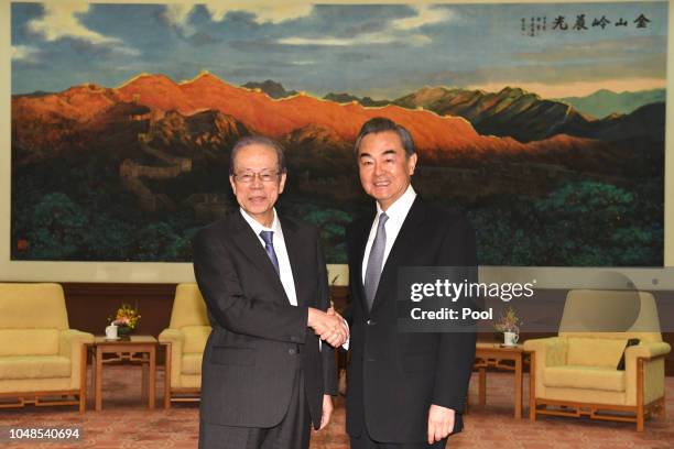 Japan's former Prime Minister Yasuo Fukuda shakes hands with Chinese State Councilor and Foreign Minister Wang Yi before their meeting at the Great...