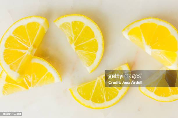 lemon wedges on marble cutting board, lemon slices shot on white background, lemons, citrus fruit, citrus fruits - lemon slices fotografías e imágenes de stock