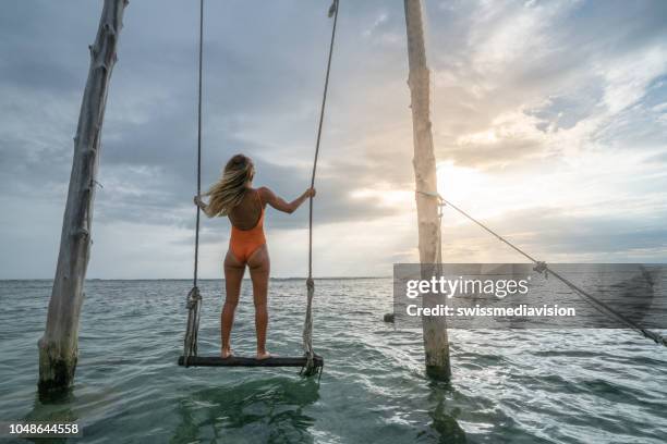 young woman swinging over the sea, beautiful and idyllic landscape. people travel vacations concept. - gili trawangan stock pictures, royalty-free photos & images