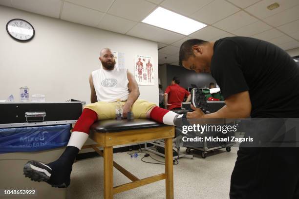 Erik Magnuson of the San Francisco 49ers gets tapped up by Assistant Head Athletic Trainer Manny Rivera in the locker room prior to the game against...