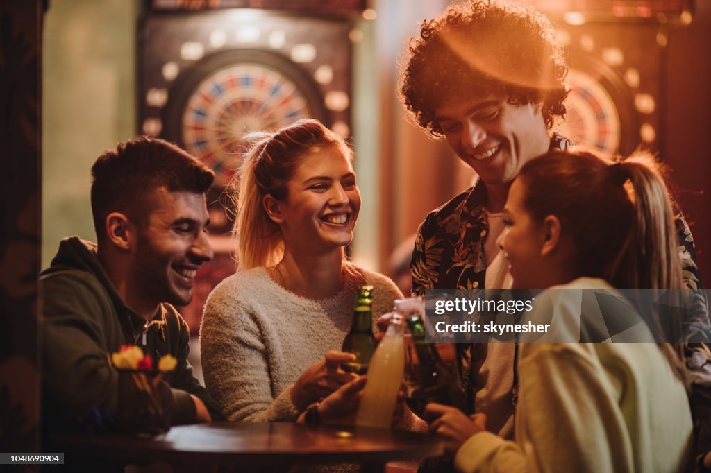 Jonge vrolijke vrienden roosteren na het Darten spelen in een bar.