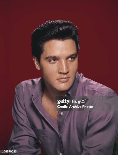 Portrait of American singer and actor Elvis Presley wearing a purple shirt circa 1956.