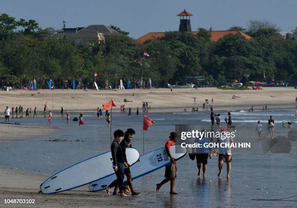 Surfers walk with their boards towards the water on Kuta beach on October 10 where the International Monetary Fund and World Bank annual meetings are...