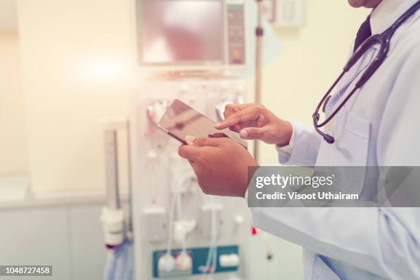 doctor is working with tablet computer at the hospital emergency room - informe-médico fotografías e imágenes de stock
