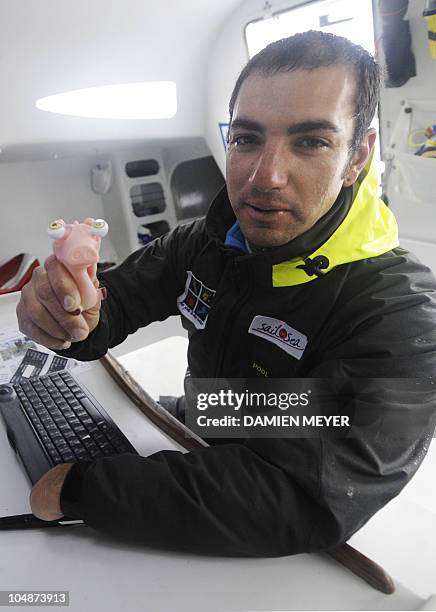 French skipper Damien Seguin poses with his mascot as he sails on his "Des pieds et des mains" monohull on October 4, 2010 off the coast of Saint...