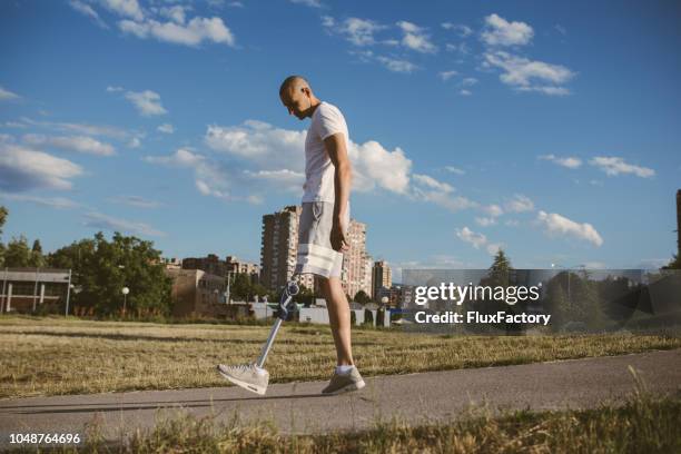 jeune homme avec une jambe artificielle à pied - amputé photos et images de collection