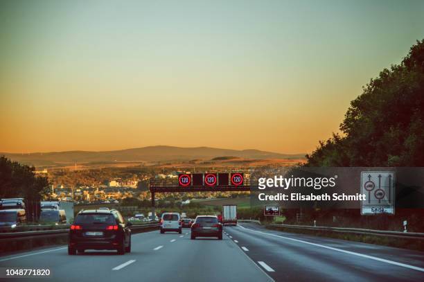 driving on a freeway / motorway / "autobahn" at sunset - speed limit sign stock pictures, royalty-free photos & images