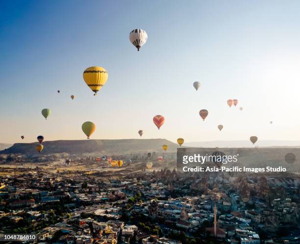 aerial view of hot air balloons flying over cappadocia at sunrise，turkey - blowing balloon stock pictures, royalty-free photos & images