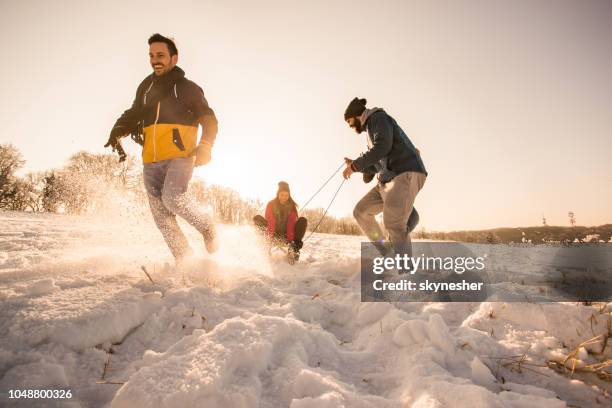 below view of playful friends having fun on snow at sunset. - recreational equipment stock pictures, royalty-free photos & images