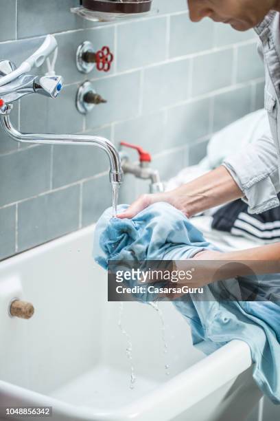 vrouw schoonmaken gekleurd shirt in badkamer wastafel - hand wash stockfoto's en -beelden