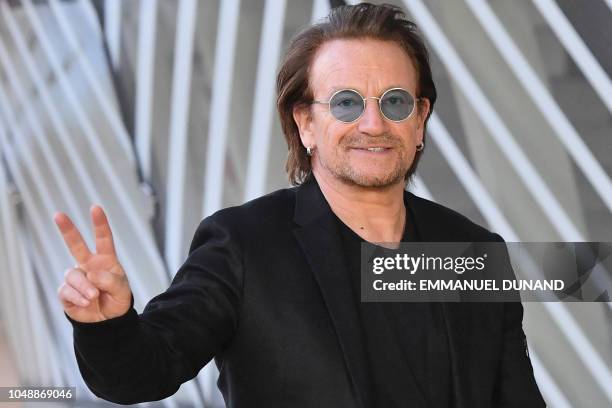 Irish rock band U2 singer Bono flashes the Victory sign upon his arrival at the European Council in Brussels on October 10, 2018. - Bono, the...