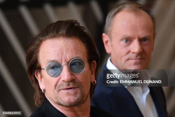 Irish rock band U2 singer Bono looks on past European Council President Donald Tusk upon his arrival at the European Council in Brussels on October...