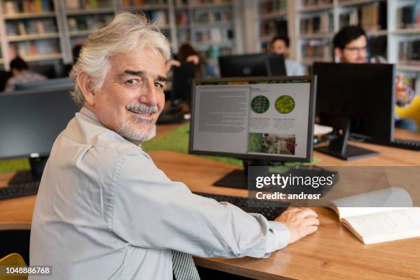 senior woman bei online-recherchen in der bibliothek - two men studying library stock-fotos und bilder