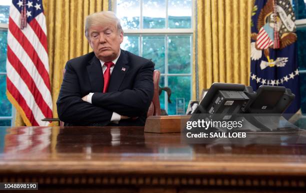 President Donald Trump sits at the Resolute Desk during a briefing on Hurricane Michael in the Oval Office of the White House in Washington, DC,...