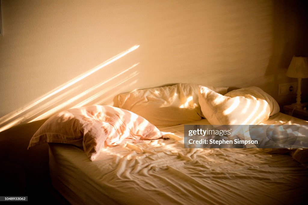 Sunlight on messy bed in home