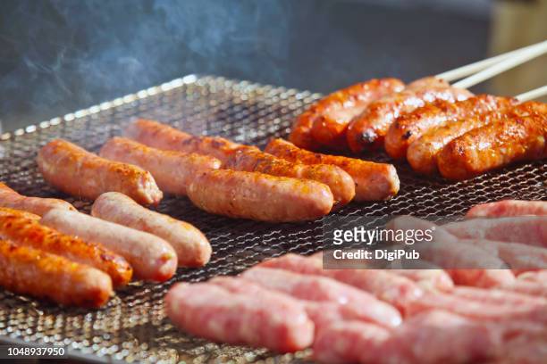 sausages on grill grate being grilled on the street at event - raw sausages stock pictures, royalty-free photos & images