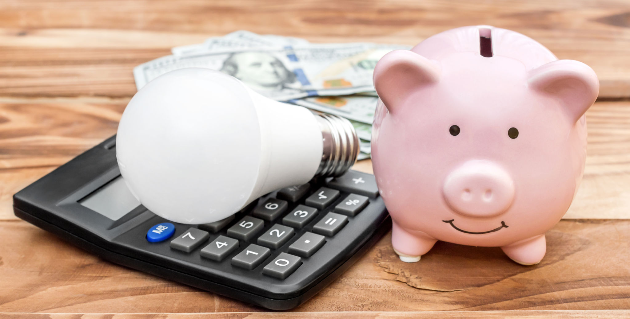 Piggy bank with light bulb, calculator and money on wooden background. Piggy bank with light bulb, calculator and money on wooden background.