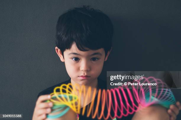 boy holding a colourful slinky - metal coil toy stockfoto's en -beelden