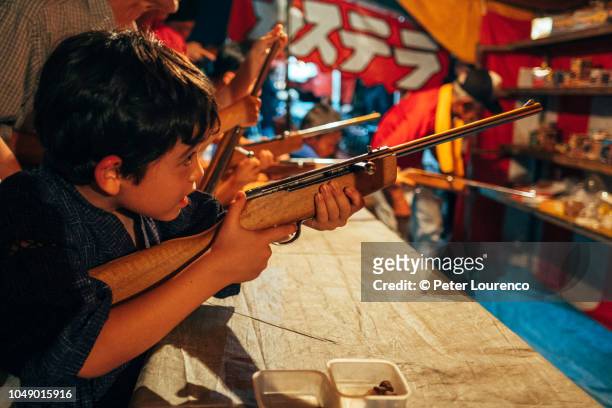 boy at fairground shooting gallery - target sport stock pictures, royalty-free photos & images