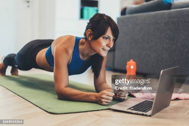 Young woman doing a plank on a yoga mat. Water bottle and …