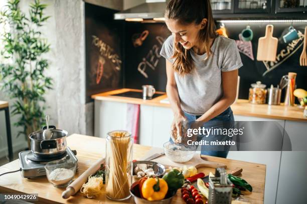 jeune femme préparant une pizza - cuisiner photos et images de collection