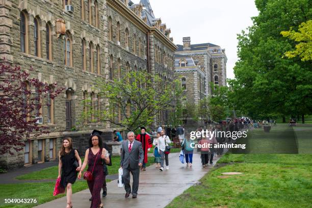 students and their family members walking in the campus of cornell university on commencement day - cornell university campus stock pictures, royalty-free photos & images