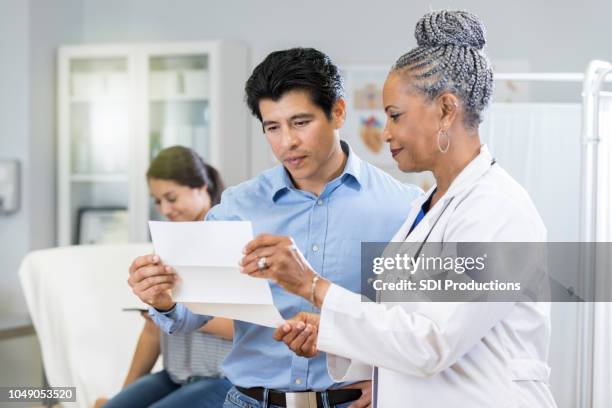 doctor reviews test results with concerned father - financial bill stock pictures, royalty-free photos & images
