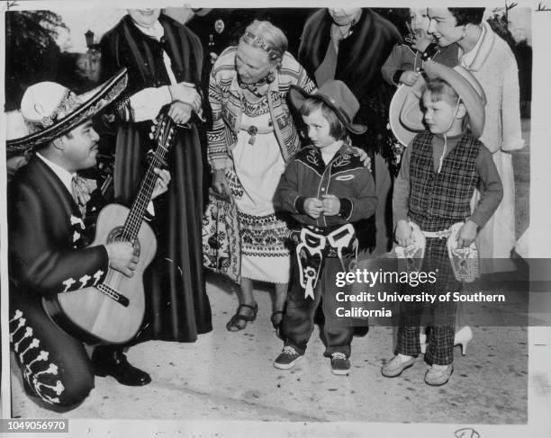 Photograph of Don Juan Benavides singing to children in Pasadena City Hall plaza. 'Pasadena marking its 75th birthday. Pasadena -- This city's 75th...