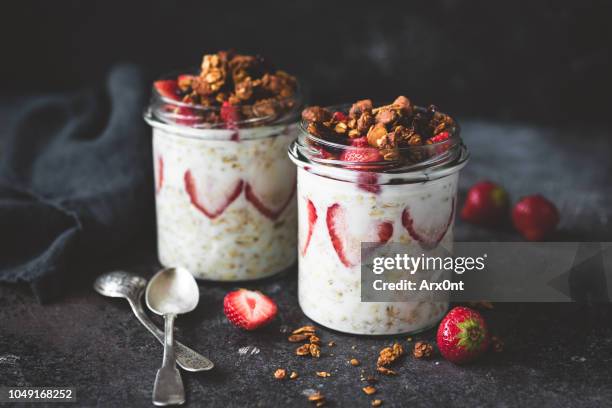 overnight oats with strawberries and granola in jar - haferflocken stock-fotos und bilder